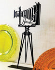 Steel decorative gift item featuring a professional camera with a stand