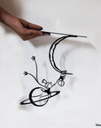 Steel decorative gift item featuring a man and a woman hanging on a moon and planet