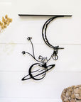 Steel decorative gift item featuring a man and a woman hanging on a moon and planet