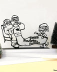 Steel decorative gift item featuring two elves showing Santa Clause who their favorite family is