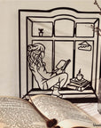 Steel decorative gift item featuring a woman reading a book and drinking coffee