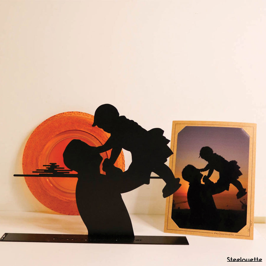 Steel decorative gift item featuring a father holding his child at sunset