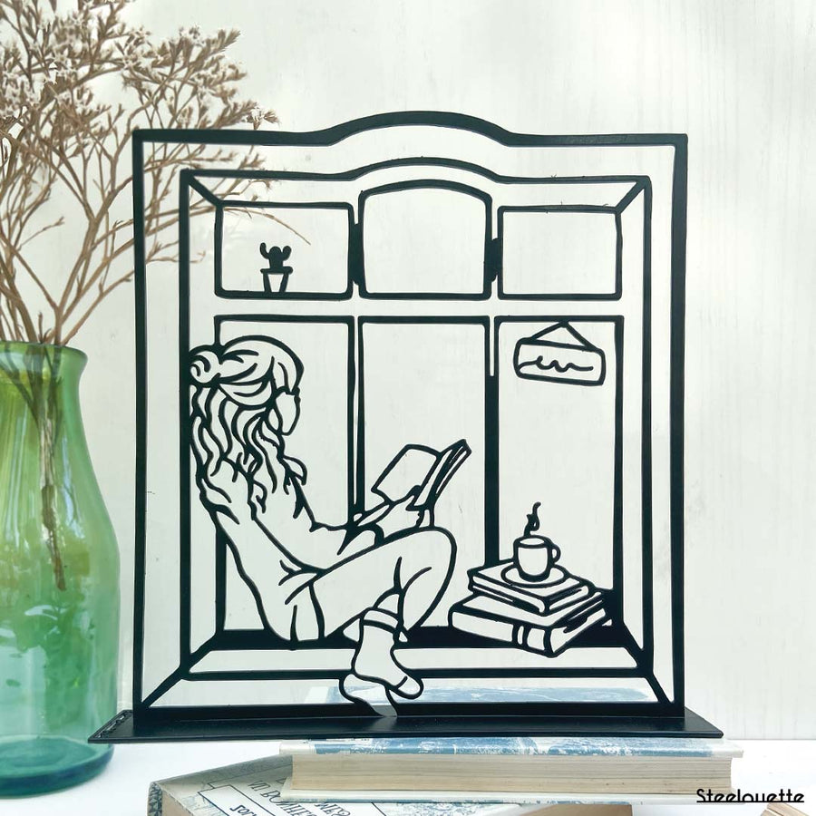 Steel decorative gift item featuring a woman reading a book and drinking coffee